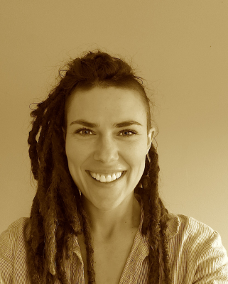 Golden tinted photo of a woman smiling with long hair. Wearing a stripped v-neck shirt. In front of a plain background.