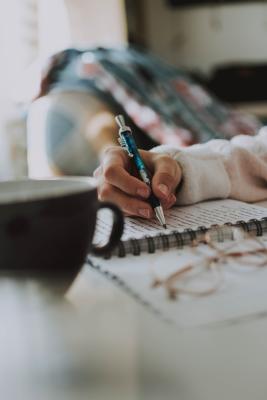 Person with coffee cup and journal and pen