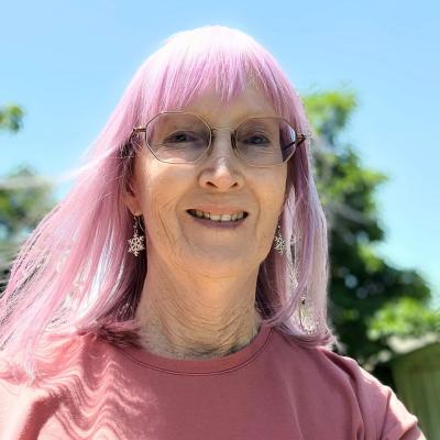 Smiling woman with pink hair in sunshine